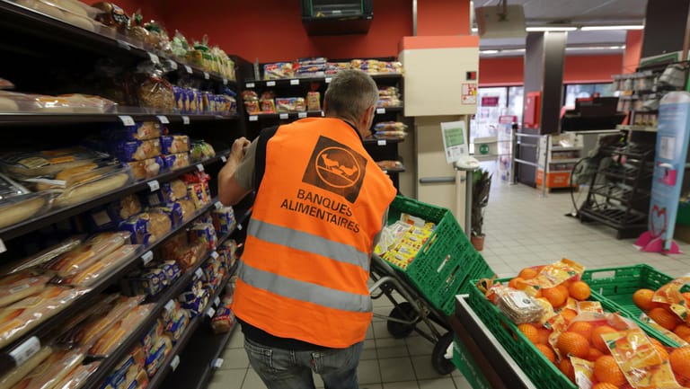 Ein Mitarbeiter von „Banques Alimentaires“ schiebt mehrere Kisten mit Essen durch einen französischen Supermarkt. Alle größeren Supermärkte sind seit 2 Jahren dazu verpflichtet, unverkauftes Essen zu verschenken.