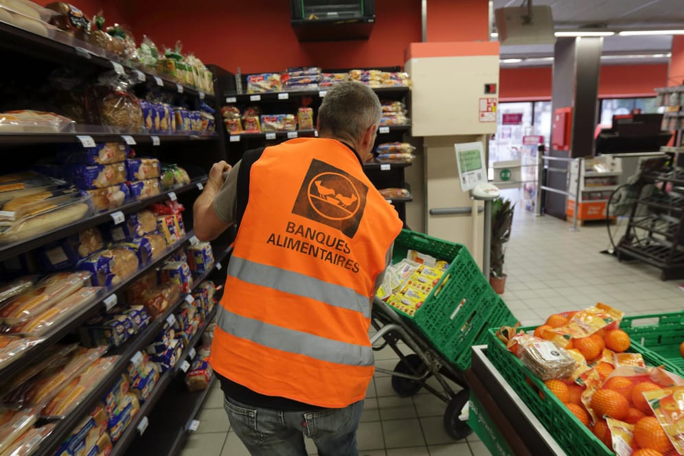Ein Mitarbeiter von „Banques Alimentaires“ schiebt mehrere Kisten mit Essen durch einen französischen Supermarkt. Alle größeren Supermärkte sind seit 2 Jahren dazu verpflichtet, unverkauftes Essen zu verschenken.