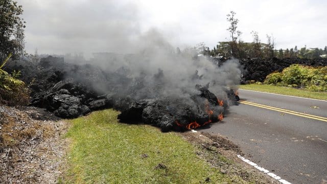Nach dem Ausbruch des Kilauea auf Hawaii walzt sich ein Lavastrom über eine Straße. Nach dem Ausbruch des Kilauea auf Hawaii walzt sich ein Lavastrom über eine Straße.