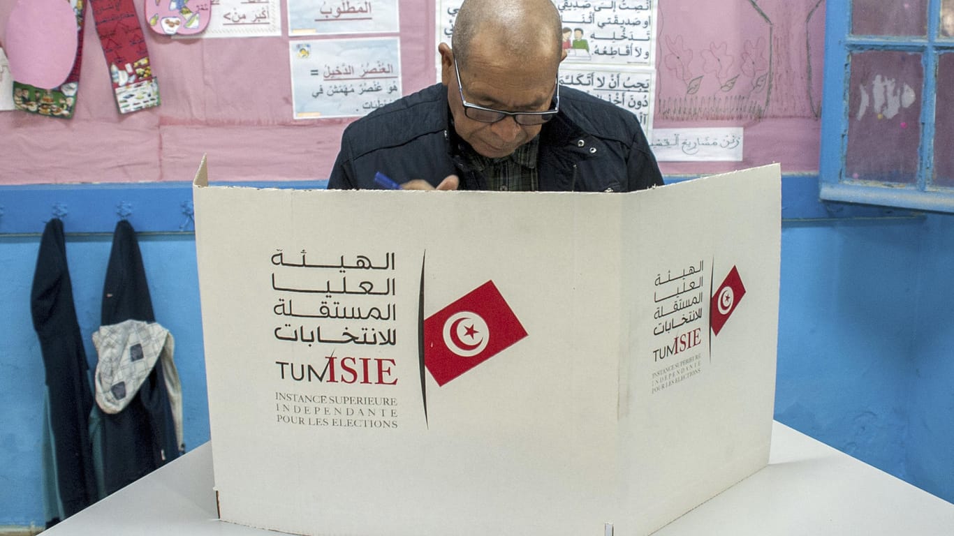 Ein Mann bereitet sich vor, seine Stimme in einem Wahllokal abzugeben. Nach ersten Prognosen liegen die islamisch-konservative Partei Ennahda (Wiedergeburt) vorn.