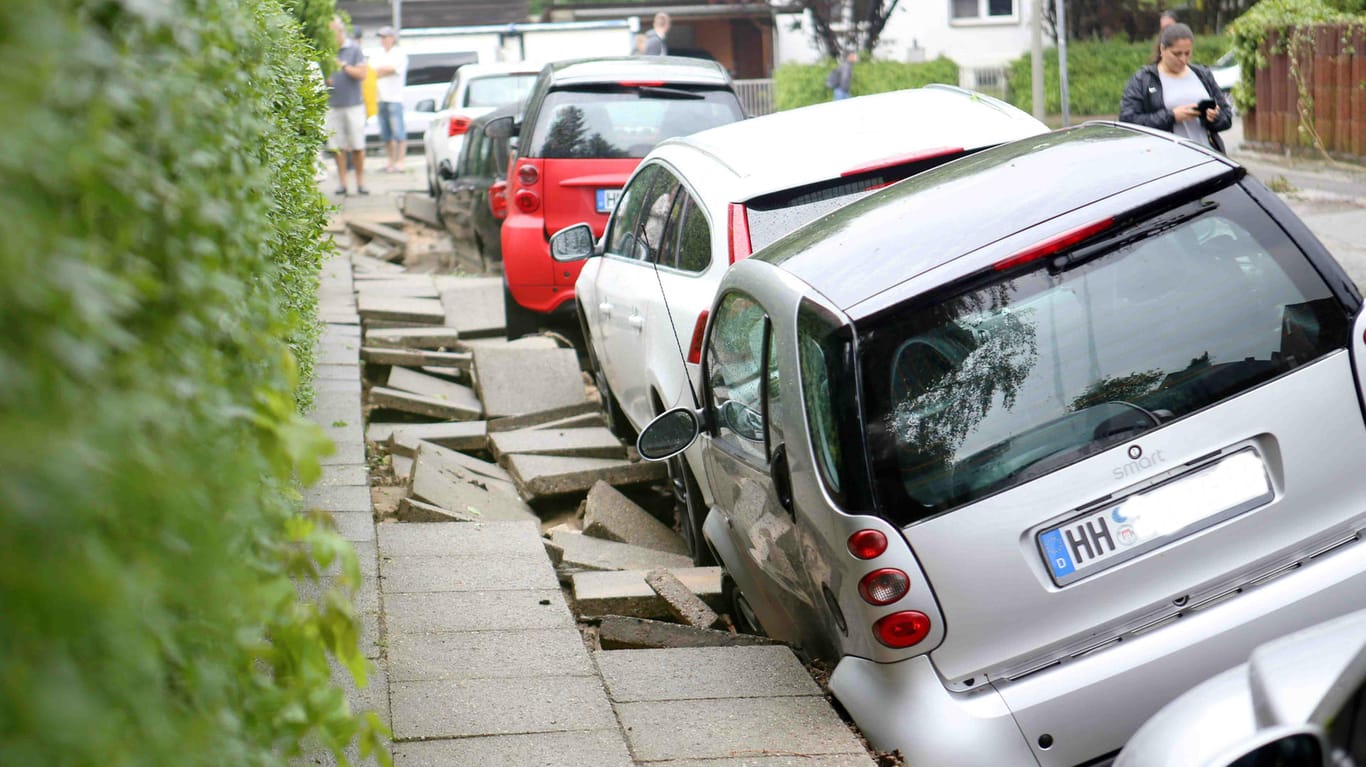 Autos stehen nach dem Unwetter an einer unterspülten Straße in Hamburg-Bergedorf.