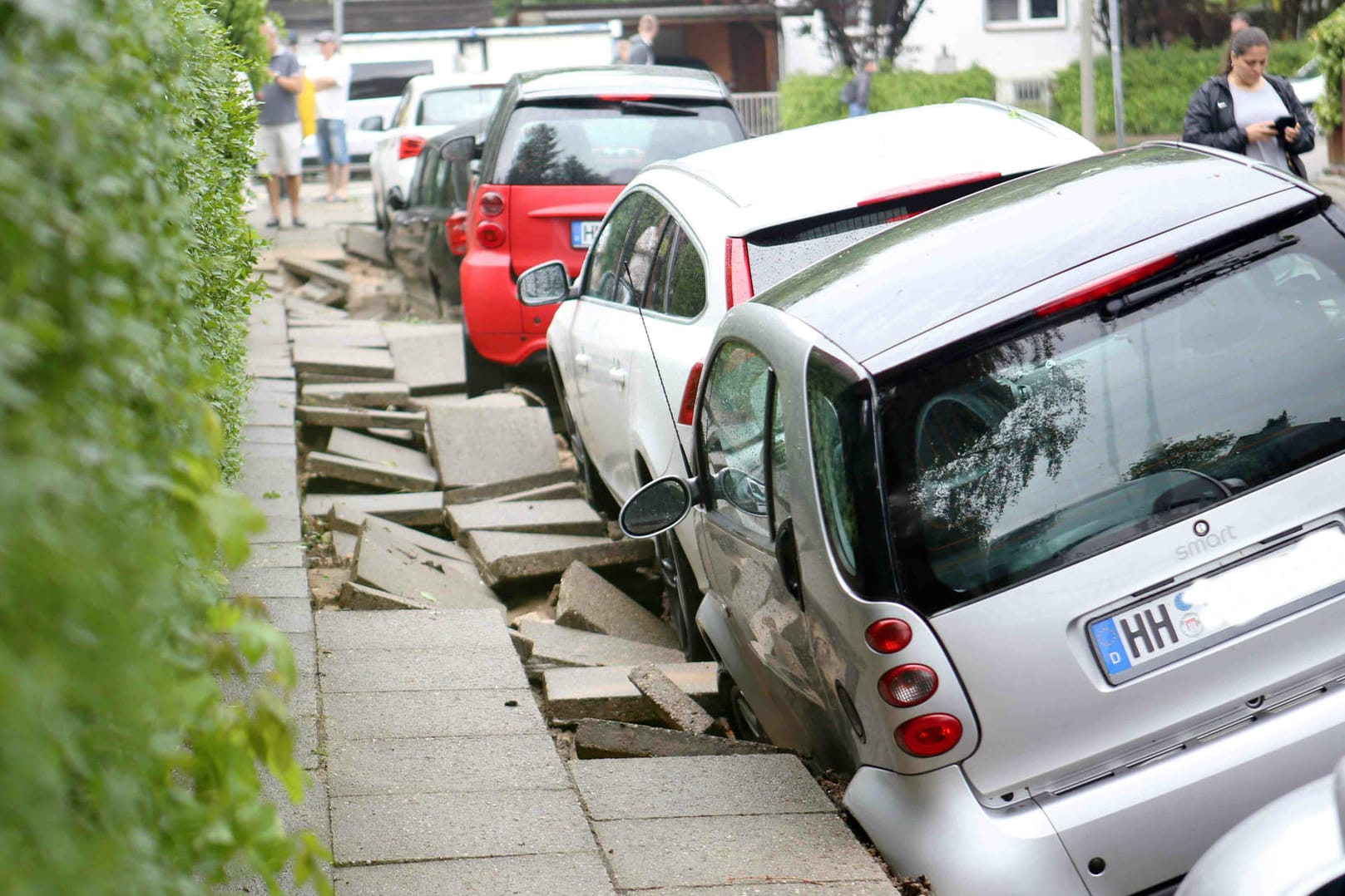 Autos stehen nach dem Unwetter an einer unterspülten Straße in Hamburg-Bergedorf.