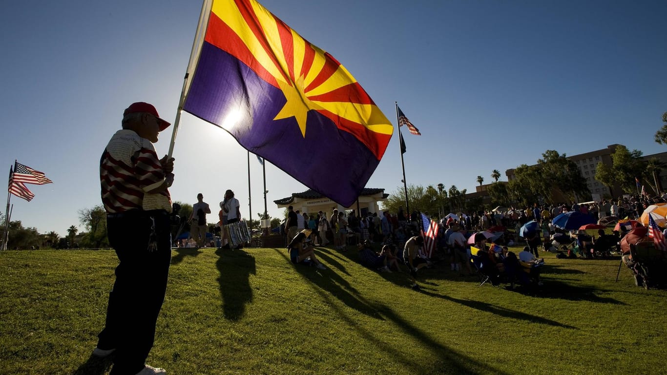 Ein Mann schwenkt die Flagge des US-Bundesstaates Arizona.