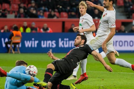 Augsburgs-Keeper Andreas Luthe (l) prallt mit Leverkusens Kevin Volland (M) zusammen.