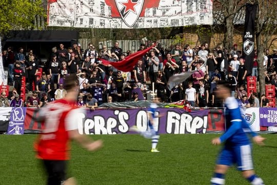 Fußballfans der Tennis Borussia Berlin (r) schauen sich mit Fans von Roter Stern Leipzig gemeinsam ein Spiel gegen den VfB Zwenkau an.