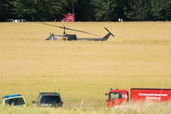 Einsatzfahrzeuge und ein Hubschrauber der Bundeswehr nahe der Absturzstelle.