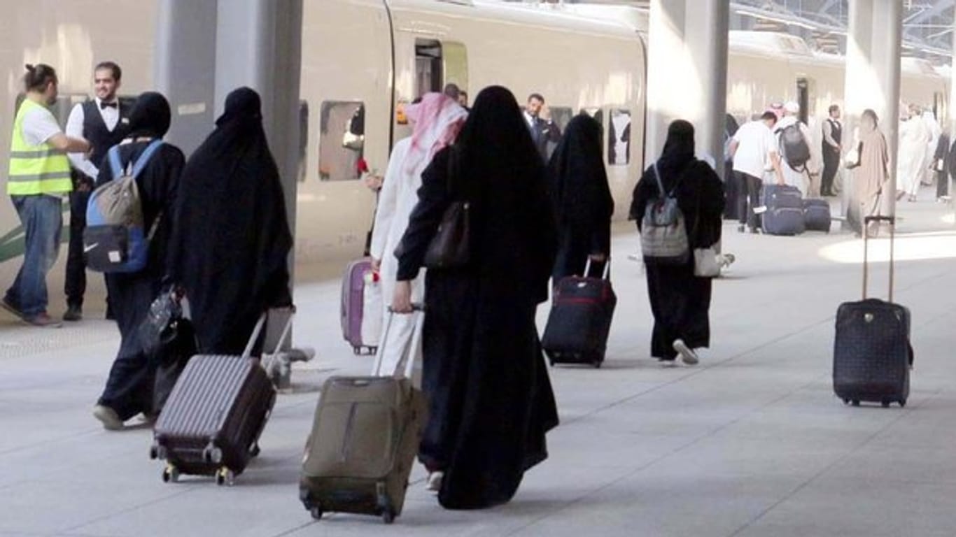 Saudische Frauen mit Ganzkörperschleier ziehen ihre Rollkoffer über einen Bahnsteig in Medina.