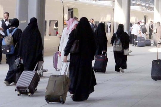 Saudische Frauen mit Ganzkörperschleier ziehen ihre Rollkoffer über einen Bahnsteig in Medina.