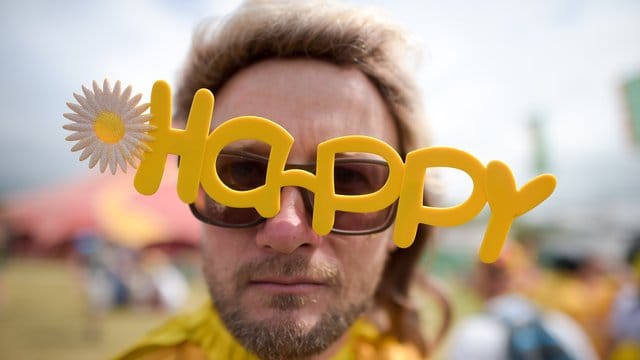 Ein Besucher eines Festivals in Großbritannien mit einer "Happy"-Brille. Ein Besucher eines Festivals in Großbritannien mit einer "Happy"-Brille.