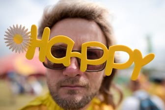 Ein Besucher eines Festivals in Großbritannien mit einer "Happy"-Brille.