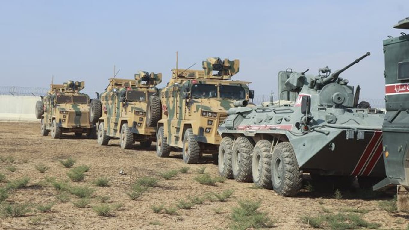 Türkische und russische Soldaten in Panzer und Militärfahrzeugen patroullieren an der türkisch-syrischen Grenze.