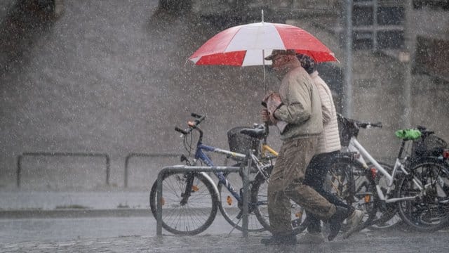 Passanten im Starkregen (Symbolbild): Der DWD warnt in Nürnberg und Umgebung unter anderem vor Gewitter.