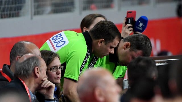 Zwei Schiedsrichter schauen beim Handball auf einen Bildschirm beim Videobeweis.