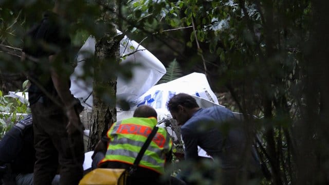 Einsatzkräfte der Polizei stehen am Wrack eines der abgestürzten Ultraleichtflugzeuge. Einsatzkräfte der Polizei stehen am Wrack eines der abgestürzten Ultraleichtflugzeuge.
