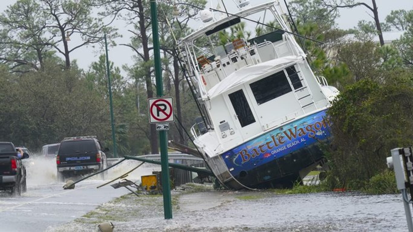Ein Boot ist durch den Hurrikan "Sally" an Land gewirbelt worden und liegt nun neben einer Straße.