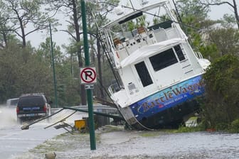 Ein Boot ist durch den Hurrikan "Sally" an Land gewirbelt worden und liegt nun neben einer Straße.