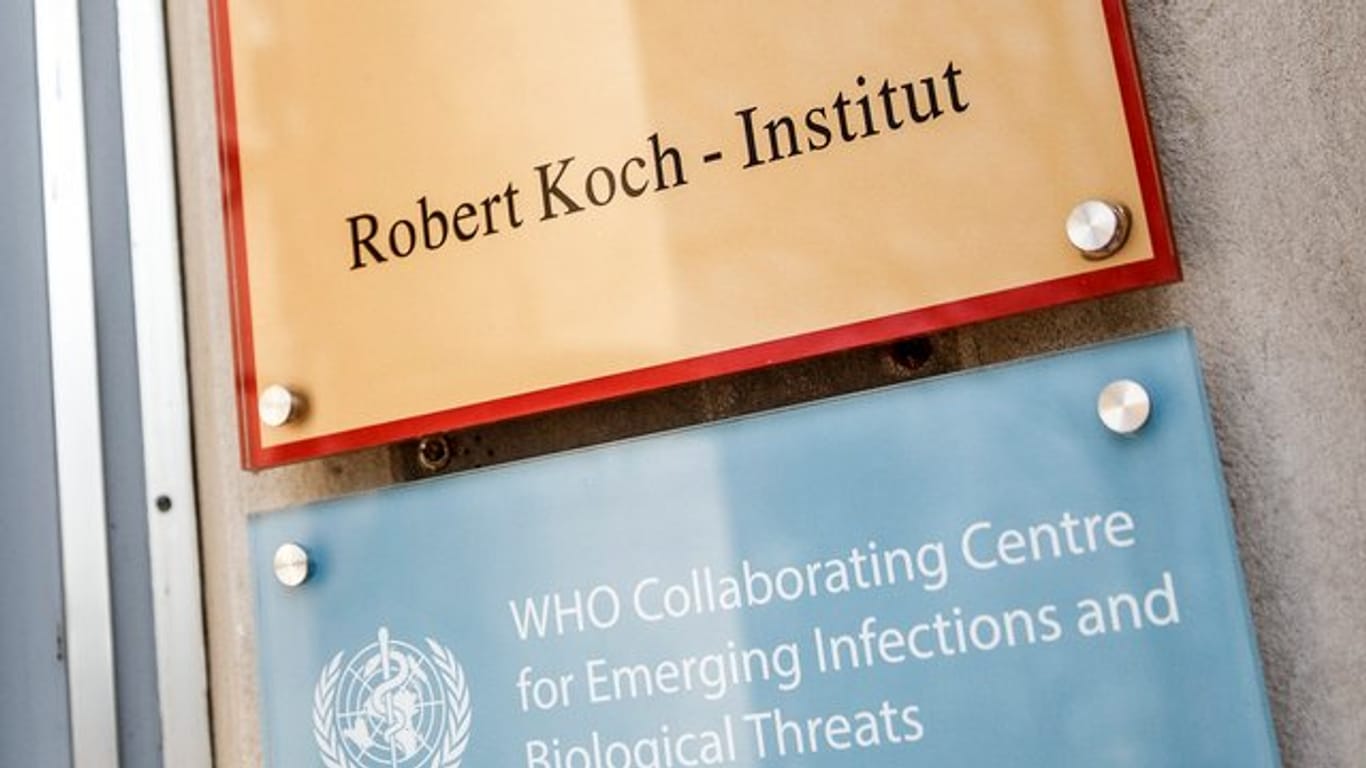 Ein Schild mit der Aufschrift "Robert Koch-Institut" weist auf den Eingang des Gebäudes hin.