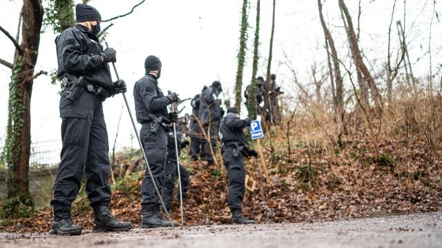 Polizisten durchsuchen einen Bahndamm in der Nähe des Parkplatzes, auf dem die Frauenleiche in einem Auto gefunden wurde.