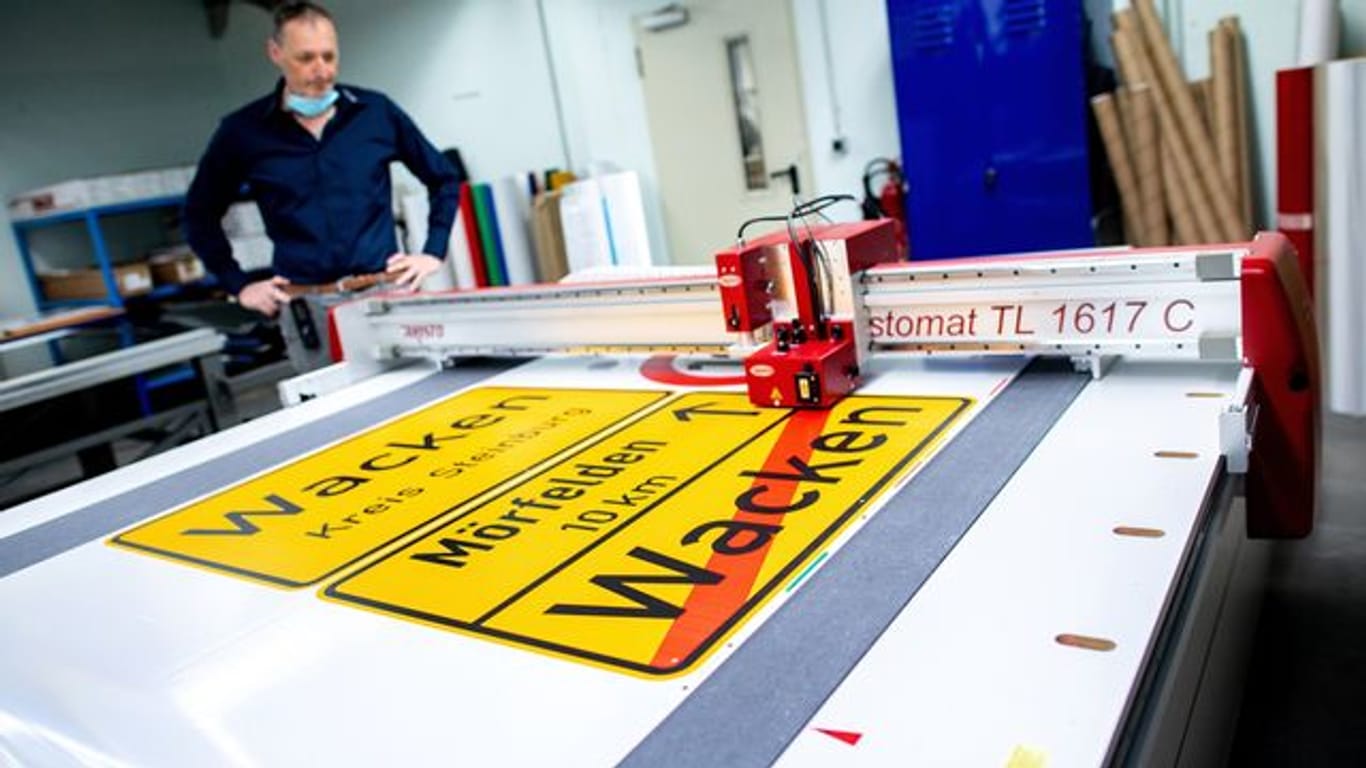 Michael Mazur, Abteilungsleiter Druckverfahren in der Fritz Lange GmbH, begutachtet den Zuschnitt einer Ortstafel von Wacken auf spezieller selbstklebender Folie.