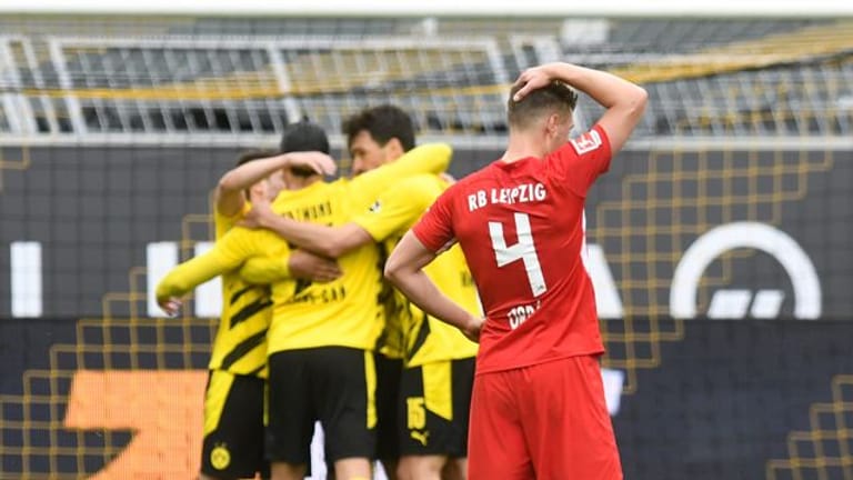Leipzigs Abwehrspieler Willi Orban fasst sich nach der Niederlage beim BVB an den Kopf - im Hintergrund feiern die Dortmunder Spieler den Sieg.