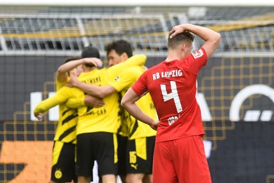 Leipzigs Abwehrspieler Willi Orban fasst sich nach der Niederlage beim BVB an den Kopf - im Hintergrund feiern die Dortmunder Spieler den Sieg.