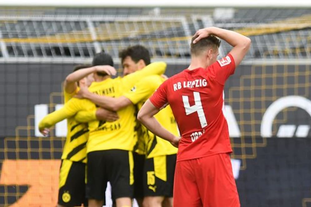 Leipzigs Abwehrspieler Willi Orban fasst sich nach der Niederlage beim BVB an den Kopf - im Hintergrund feiern die Dortmunder Spieler den Sieg.
