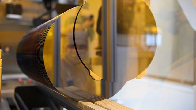 Ein Mitarbeiter spiegelt sich während eines Presserundgangs in der neuen Halbleiterfabrik von Bosch im Reinraum in einem 300-Millimeter-Wafer. Ein Mitarbeiter spiegelt sich während eines Presserundgangs in der neuen Halbleiterfabrik von Bosch im Reinraum in einem 300-Millimeter-Wafer.
