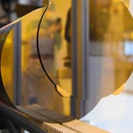 Ein Mitarbeiter spiegelt sich während eines Presserundgangs in der neuen Halbleiterfabrik von Bosch im Reinraum in einem 300-Millimeter-Wafer.