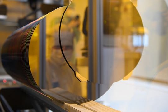 Ein Mitarbeiter spiegelt sich während eines Presserundgangs in der neuen Halbleiterfabrik von Bosch im Reinraum in einem 300-Millimeter-Wafer.