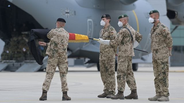 Brigadegeneral Ansgar Meyer (l), der letzte Befehlshaber der Bundeswehr in Afghanistan, rollt vor dem Transportflugzeug vom Typ Airbus A400M der Luftwaffe die Truppenfahne ein.