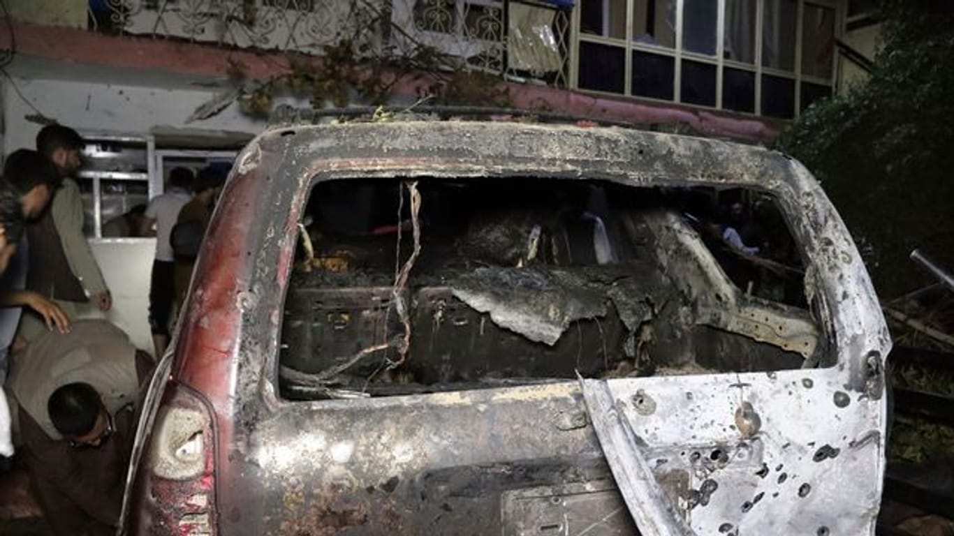 Personen betrachten ein ausgebranntes Fahrzeug in Kabul, das bei einem amerikanischen Drohnenangriff ins Visier genommen wurde.