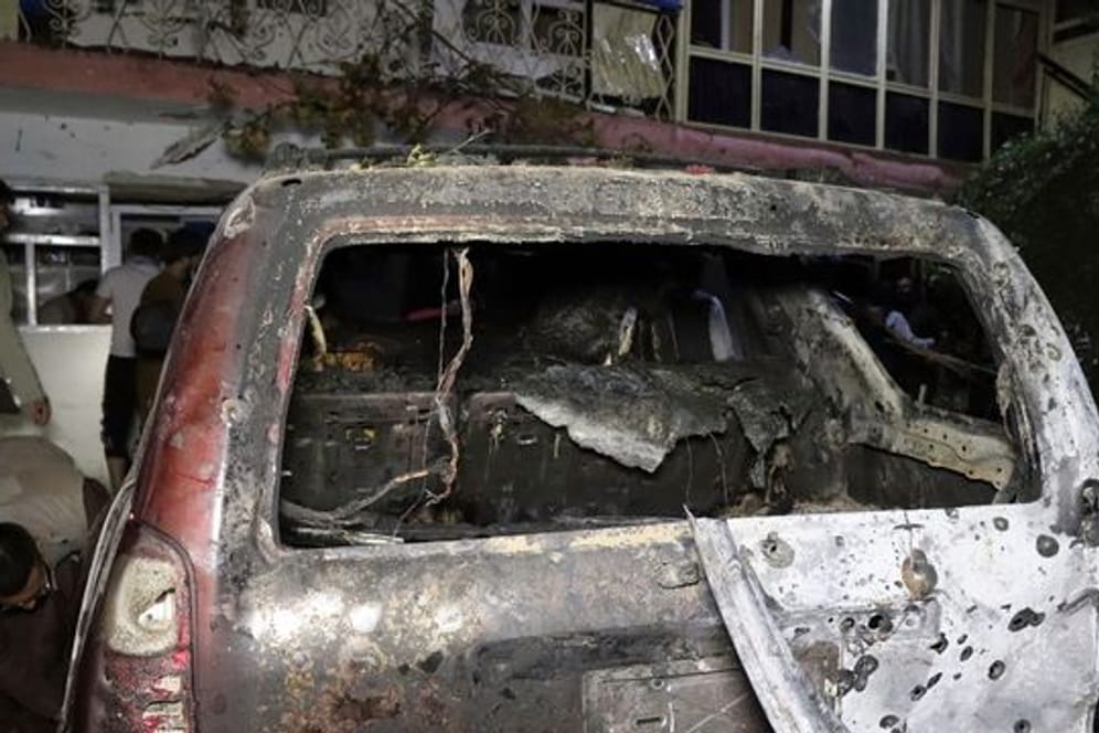 Personen betrachten ein ausgebranntes Fahrzeug in Kabul, das bei einem amerikanischen Drohnenangriff ins Visier genommen wurde.