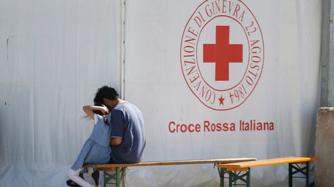 Ein Mann und ein Kind sitzen in einem Einsatzzentrum des italienischen Roten Kreuzes, Croce Rossa Italiana (CRI).