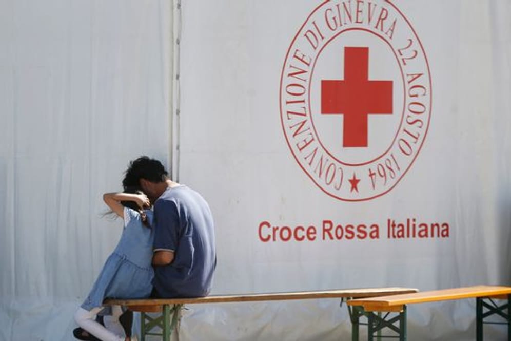Ein Mann und ein Kind sitzen in einem Einsatzzentrum des italienischen Roten Kreuzes, Croce Rossa Italiana (CRI).