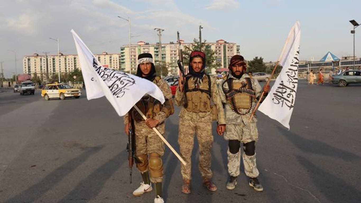 Kämpfer der Taliban stehen mit Flaggen auf einer Straße in der afghanischen Hauptstadt Kabul.