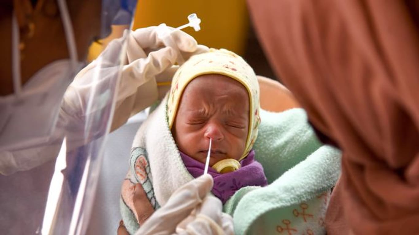 Eine Medizinerin entnimmt einem Baby in einem Krankenhaus einen Nasenabstrich für einen Corona-Test.