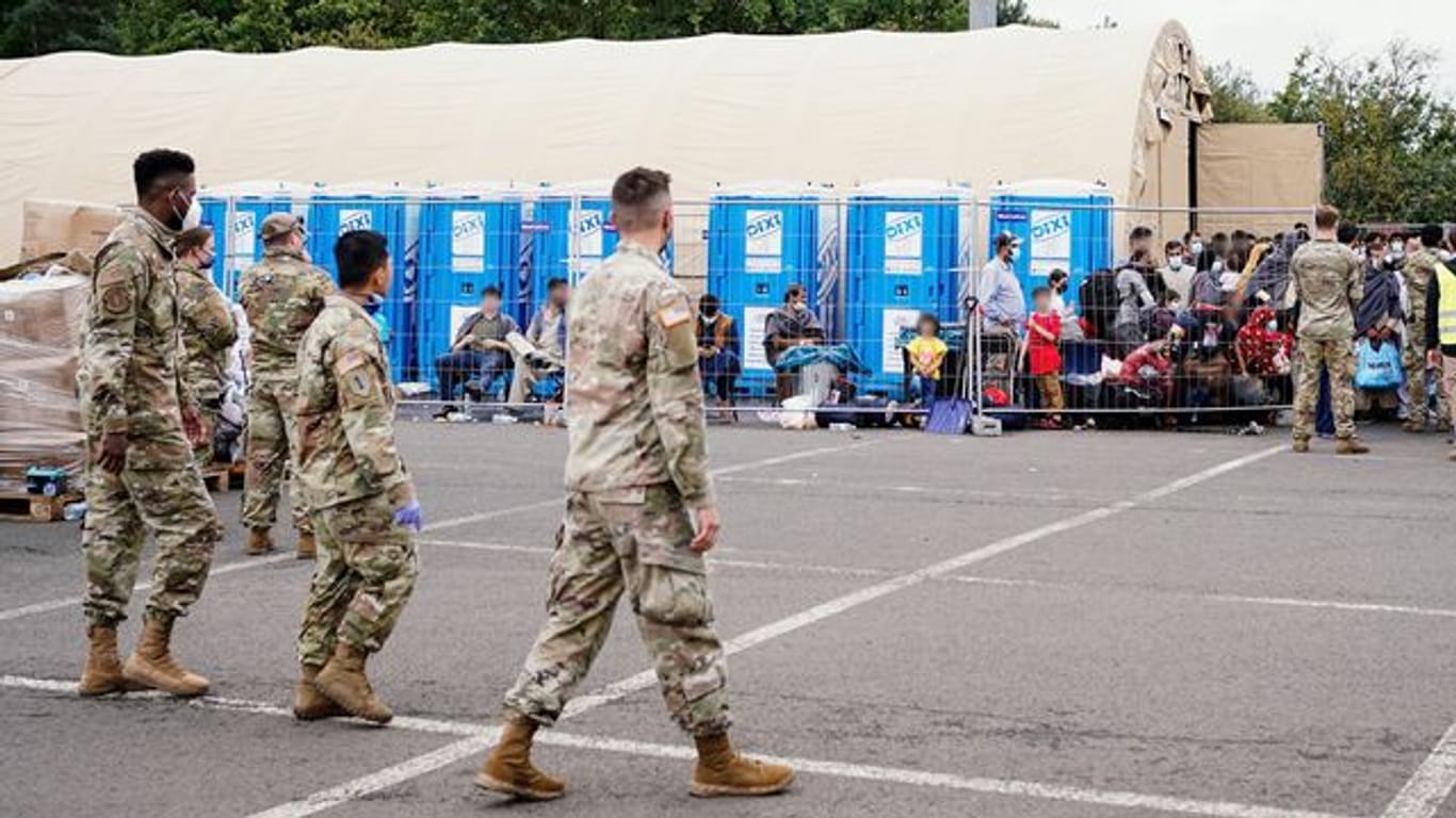 Aus Afghanistan evakuierte Menschen stehen auf der Ramstein Air Base vor einem Zelt.
