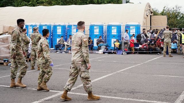 Aus Afghanistan evakuierte Menschen stehen auf der Ramstein Air Base vor einem Zelt. Aus Afghanistan evakuierte Menschen stehen auf der Ramstein Air Base vor einem Zelt.