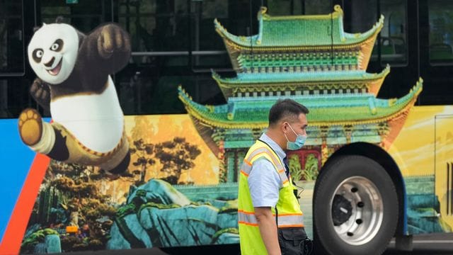 Ein Verkehrspolizist steht bei Probefahrten neben einem Bus, auf dem für den Vergnügungspark von Universal Studios geworben wird. Ein Verkehrspolizist steht bei Probefahrten neben einem Bus, auf dem für den Vergnügungspark von Universal Studios geworben wird.