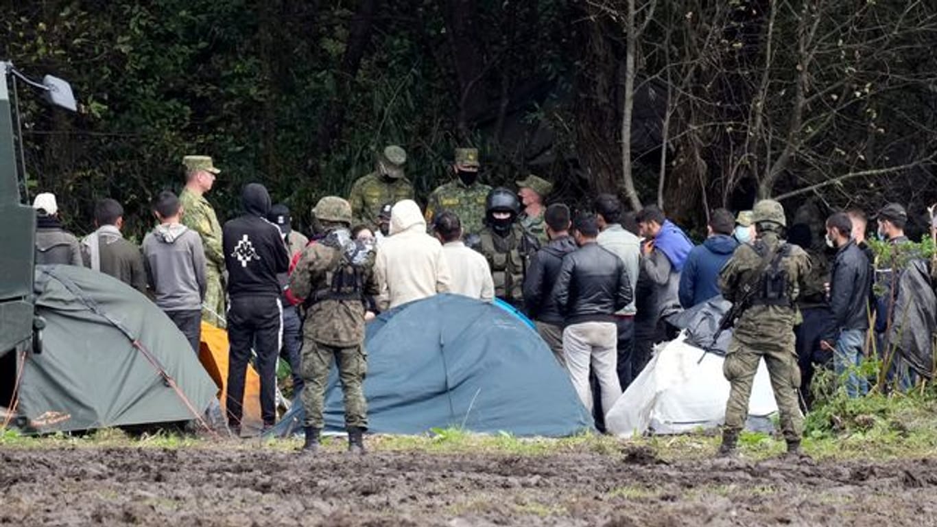 Migranten, die an der Grenze zu Belarus festsitzen, werden von polnischen Beamten umstellt.