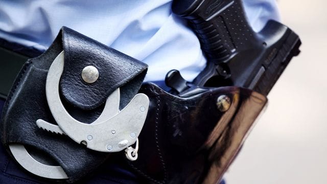 Ein Polizist mit Handschellen und Pistole am Gürtel. Ein Polizist mit Handschellen und Pistole am Gürtel.