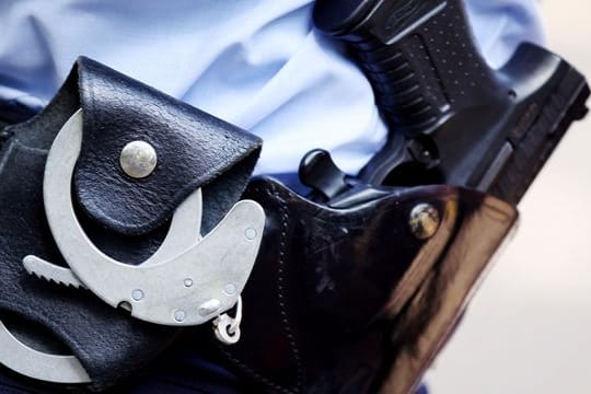 Ein Polizist mit Handschellen und Pistole am Gürtel.