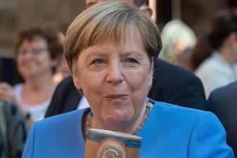 Bundeskanzlerin Angela Merkel (CDU) trinkt bei der Stralsunder Stadtwache ein Bier.