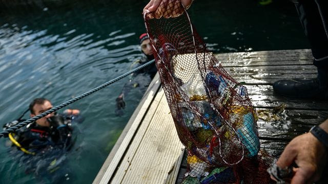 Ein Taucher hält ein Netz mit Abfällen, die er im baskischen Dorf Bermeo aus dem Meer entzogen hat. Ein Taucher hält ein Netz mit Abfällen, die er im baskischen Dorf Bermeo aus dem Meer entzogen hat.