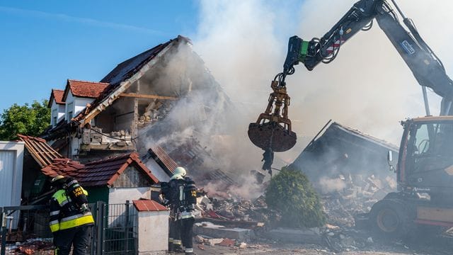 Ein Bagger räumt Teile des eingestürzten Hauses weg.