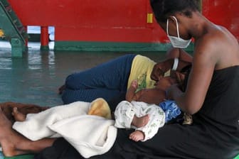 Eine Frau sitzt mit ihren Kindern an Deck des Seenotrettungsschiffs "Sea-Eye 4".