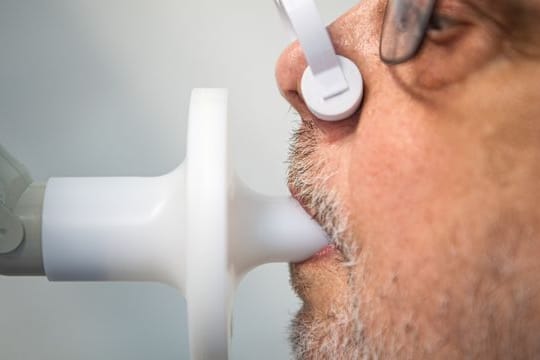 Ein Patient sitzt zur Überprüfung seiner Lungenfunktion in einem Bodyplethysmographen.