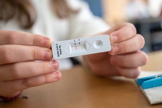 Ein Schülerin zeigt in einer Klasse ihren negativen Corona-Schnelltest.