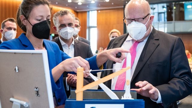 Peter Altmaier (r, CDU), Bundesminister für Wirtschaft und Energie, sieht sich das Modell einer möglichen Raketen-Startplattform der GOSA in der Nordsee an.