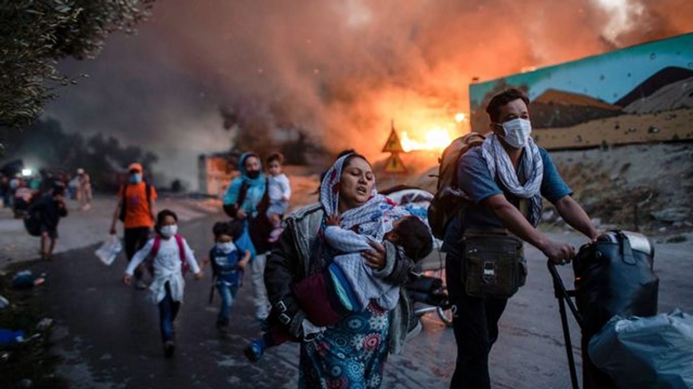 Migranten fliehen vor einem großen Feuer mit ihren Habseligkeiten aus dem Flüchtlingslager Moria.